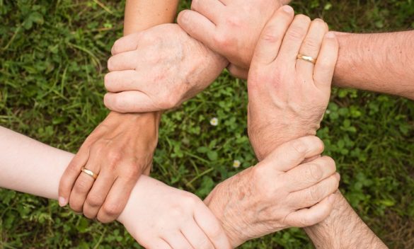 6 mani che si stringono in cerchio, prendendosi per i polsi